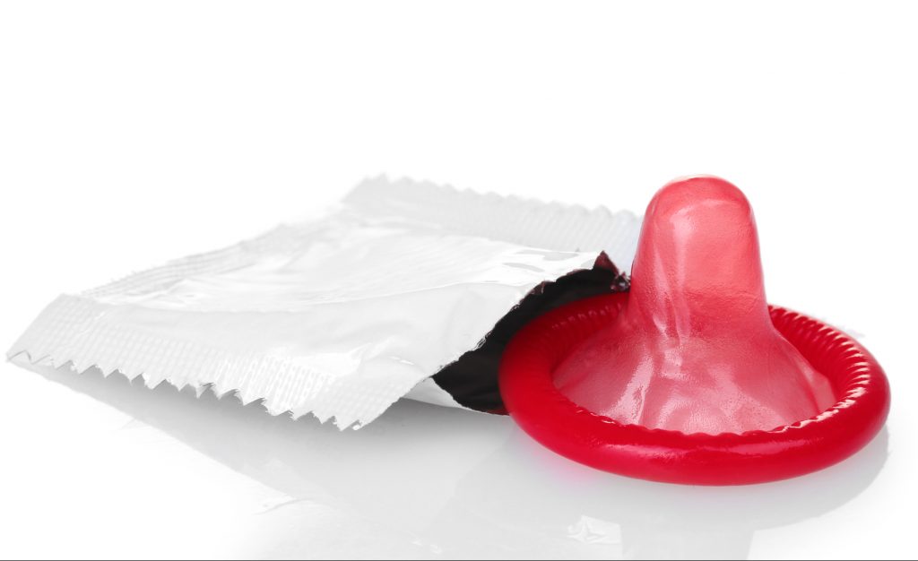 Farbiges Kondom mit geoeffneter Packung