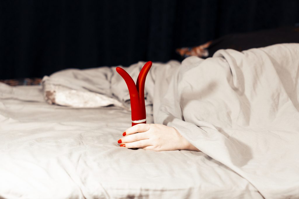 Frau im Bett mit einem Vibrator