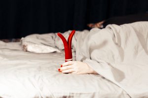 Frau im Bett mit einem Vibrator